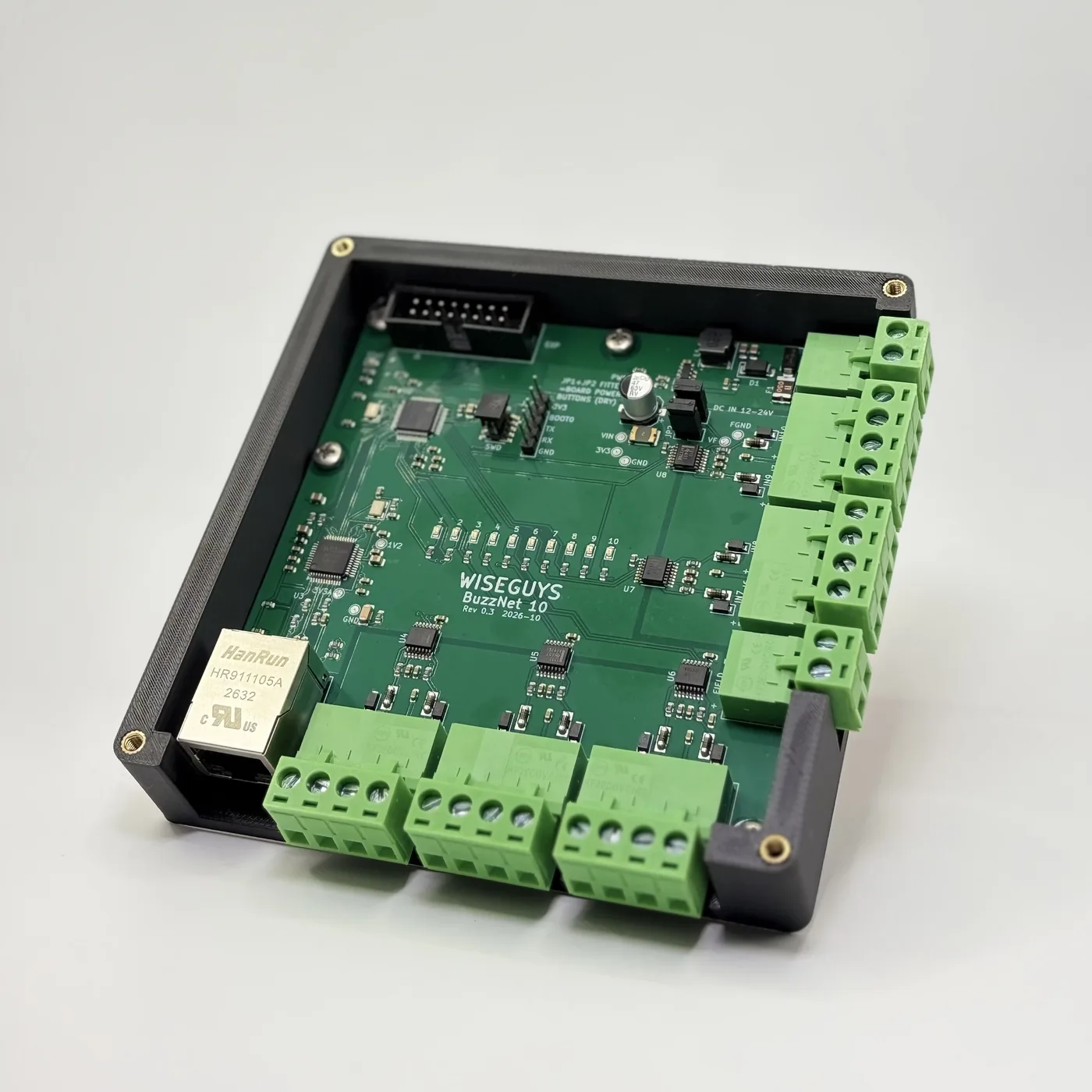 BuzzNet 10 with the lid off: the green WiseGuys board with ten input LEDs, the RJ45 network jack and the green button terminals
